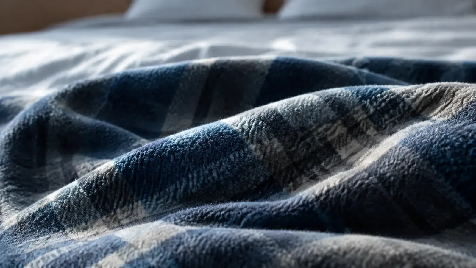 Close-up of soft gray flannel blanket texture folded on a made bed